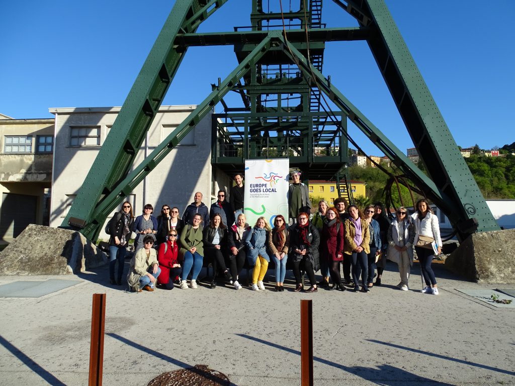 A group of people are posing outside in front of a metal structure